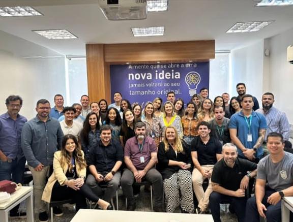 Turma de colaboradores após palestra com banner 'nova ideia'